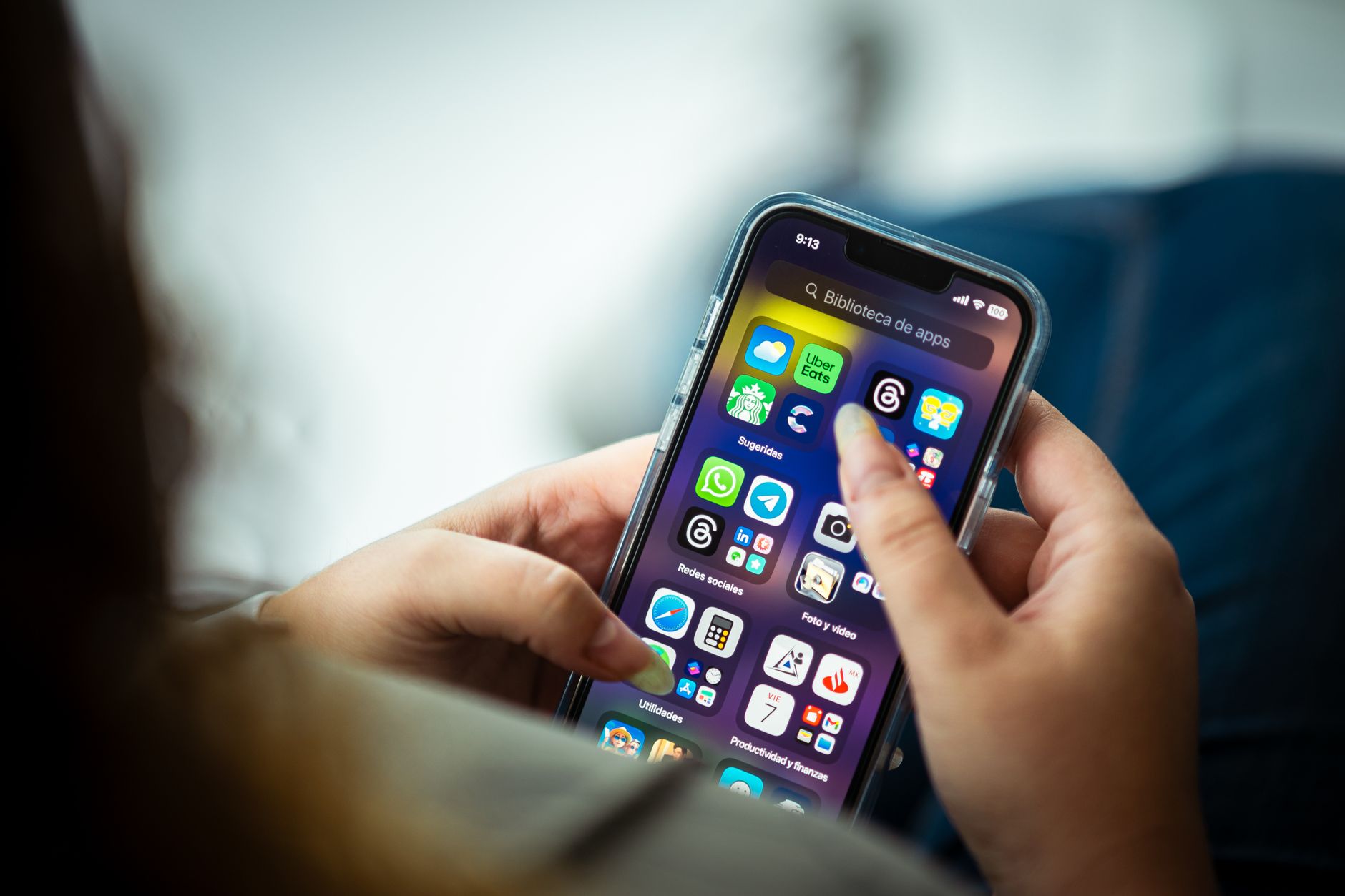 Une personne tient un smartphone dont l’écran d’accueil affiche de nombreuses applications.